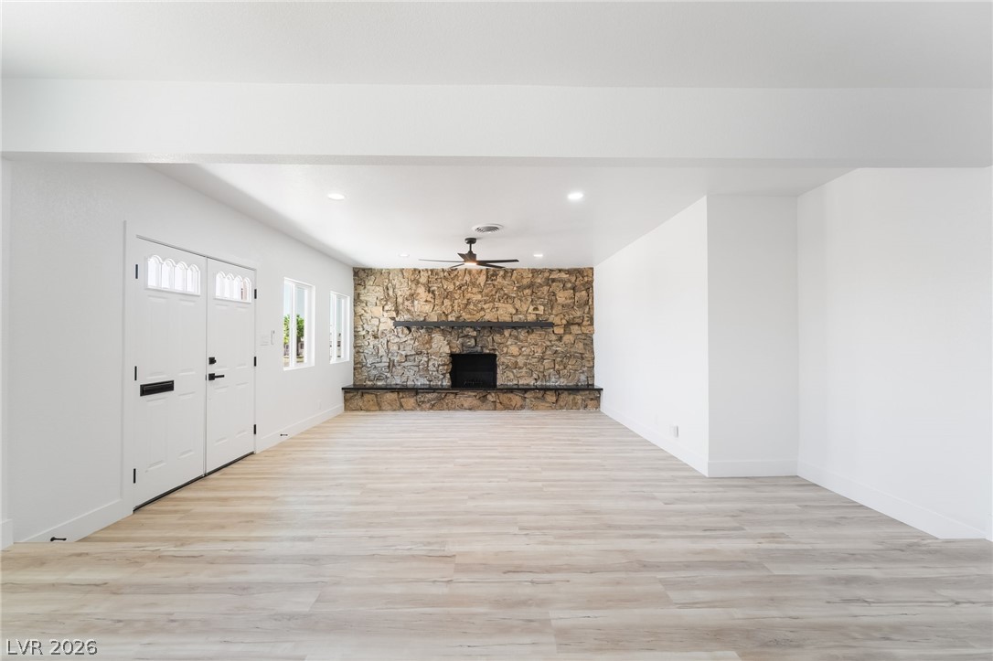 39 Lowery Street Henderson, NV 89015 - Photo 6 of 40 A spacious, naturally illuminated room features a prominent stone fireplace and light-toned flooring.