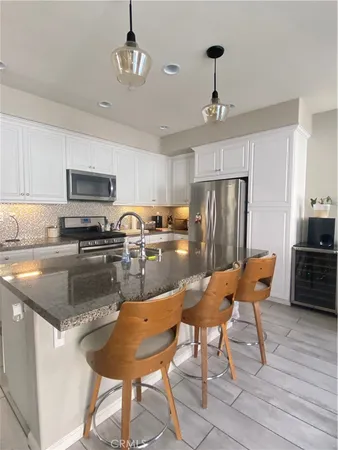 a kitchen with stainless steel appliances granite countertop a refrigerator a stove a sink dishwasher a dining table and chairs with wooden floor