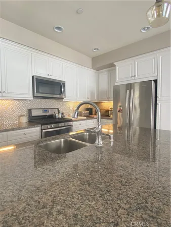 a kitchen with granite countertop a refrigerator and a stove top oven