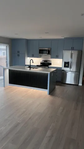 a kitchen with stainless steel appliances kitchen island granite countertop a stove a sink and a refrigerator