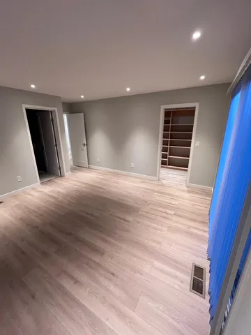 a view of an empty room with wooden floor and windows