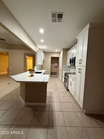 a large kitchen with kitchen island granite countertop a stove a sink a counter top space and cabinets