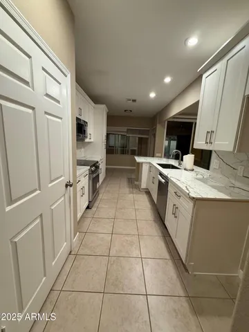 a room with kitchen island stainless steel appliances a sink a counter top space cabinets and a counter top space