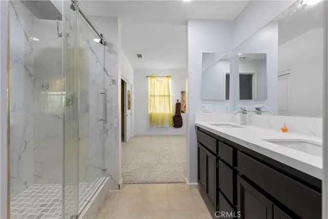 a bathroom with a granite countertop sink two mirror and shower