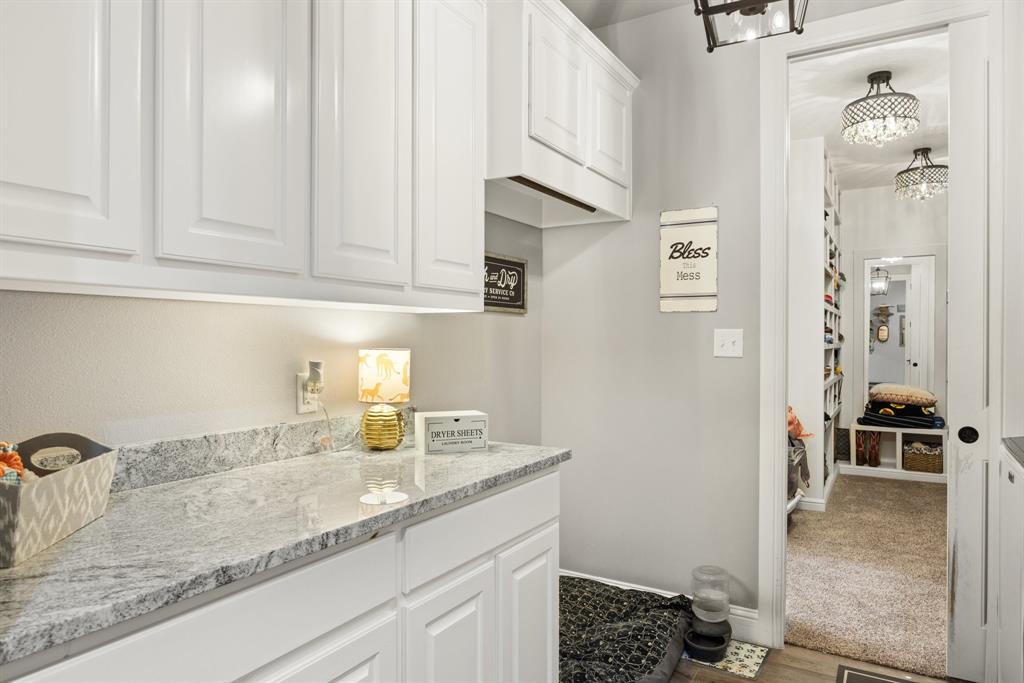 1800 Knox Road Tolar, TX 76476 - Photo 12 of 38 White shaker-style cabinetry with under-cabinet lighting, a speckled stone-finish countertop, and a built-in recessed storage niche