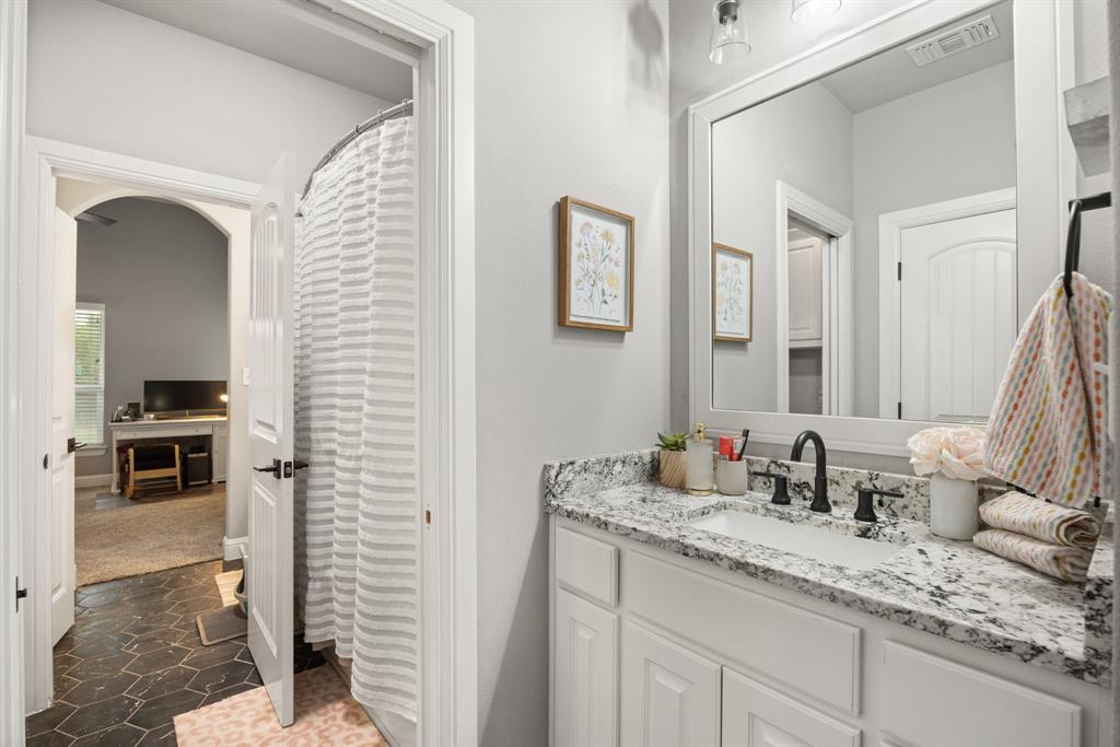 1800 Knox Road Tolar, TX 76476 - Photo 22 of 38 Bathroom #3 is a Jack & Jill bathroom featuring a white vanity with panel cabinetry, a granite-finish countertop, an undermount sink, and a matte black faucet.