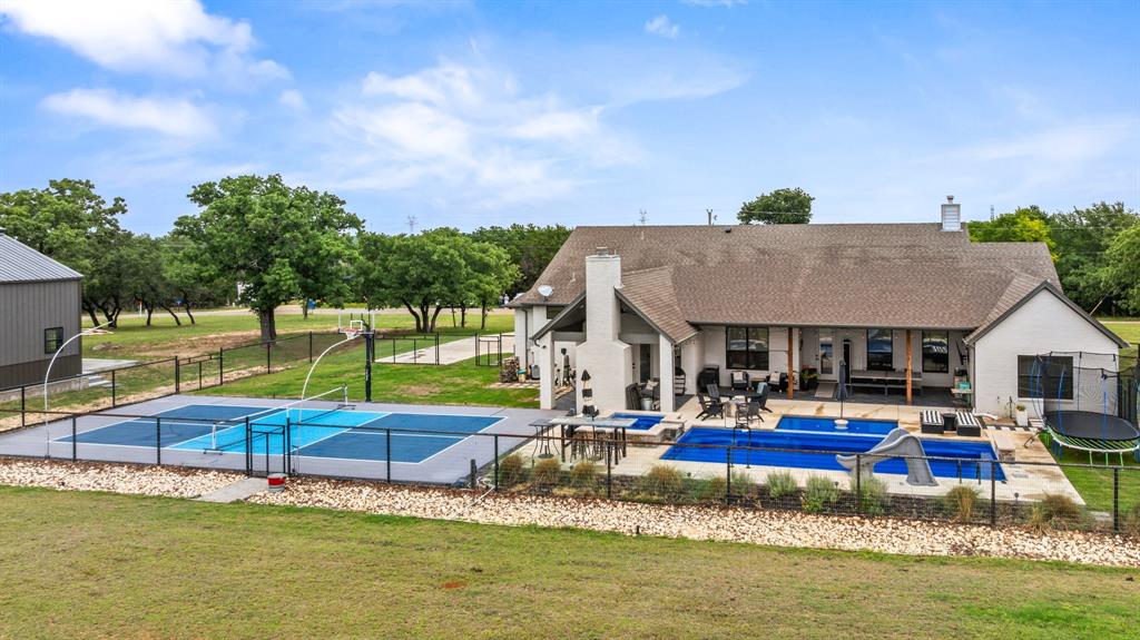1800 Knox Road Tolar, TX 76476 - Photo 28 of 38 Expansive backyard featuring a multi-sport court with basketball hoop, a fenced pool area with two pools, and an extensive covered patio
