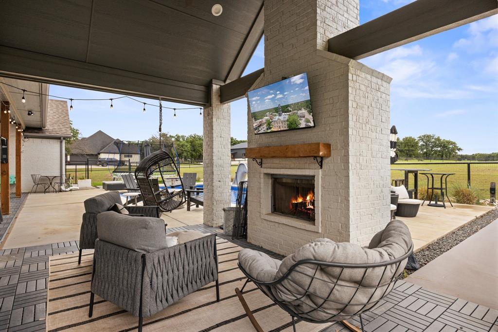 1800 Knox Road Tolar, TX 76476 - Photo 29 of 38 Covered patio featuring an outdoor fireplace with a wood mantle, an integrated television, and string lighting