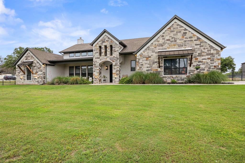 1800 Knox Road Tolar, TX 76476 - Photo 3 of 38 Stone and brick exterior featuring multiple gables, an arched entryway, and a large manicured lawn