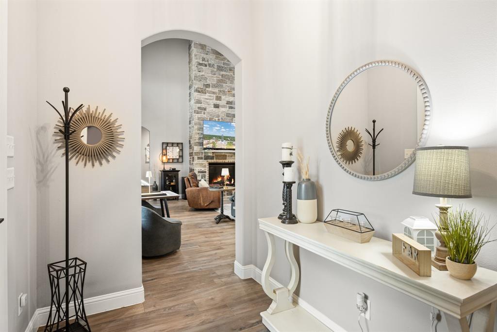 1800 Knox Road Tolar, TX 76476 - Photo 6 of 38 Archway entry leading to a living area with wood-finish flooring, a stone accent wall, and high ceilings