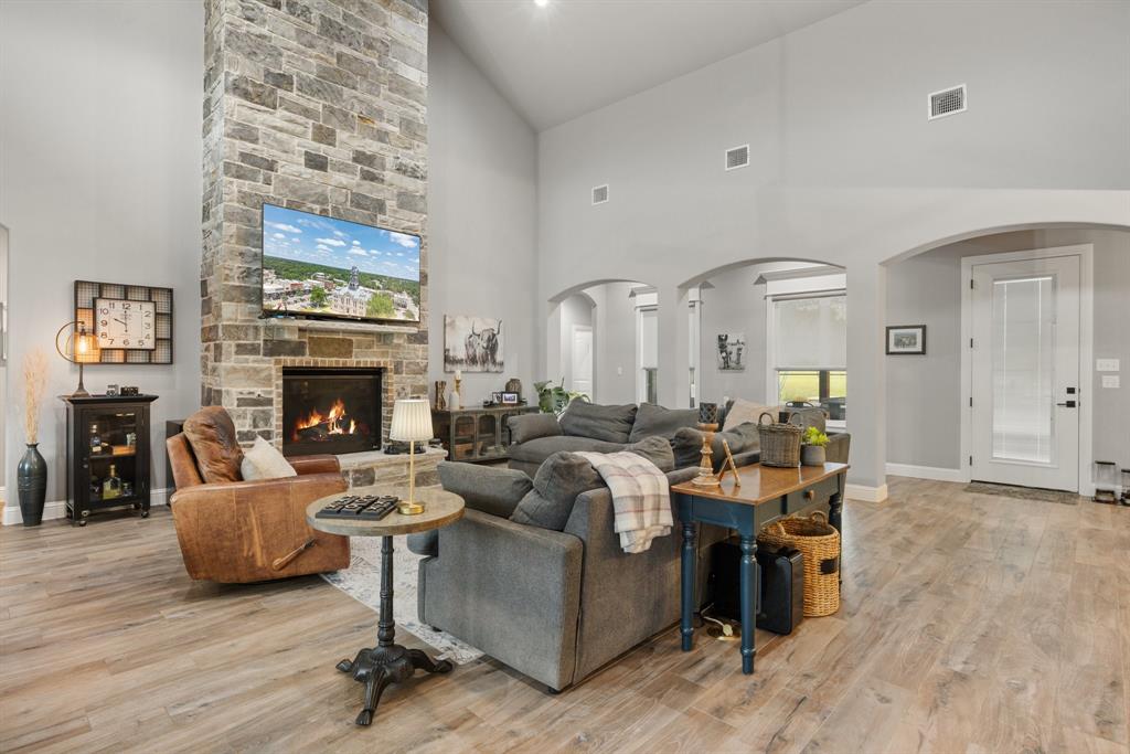 1800 Knox Road Tolar, TX 76476 - Photo 8 of 38 Spacious living area featuring a floor-to-ceiling stone fireplace, high vaulted ceilings, wood-finish flooring, recessed lighting, and arched doorways