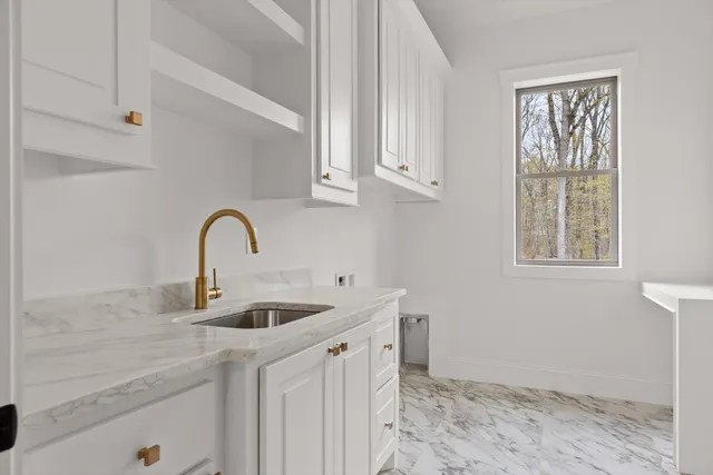 a kitchen with stainless steel appliances granite countertop a sink a stove and white cabinets with wooden floor