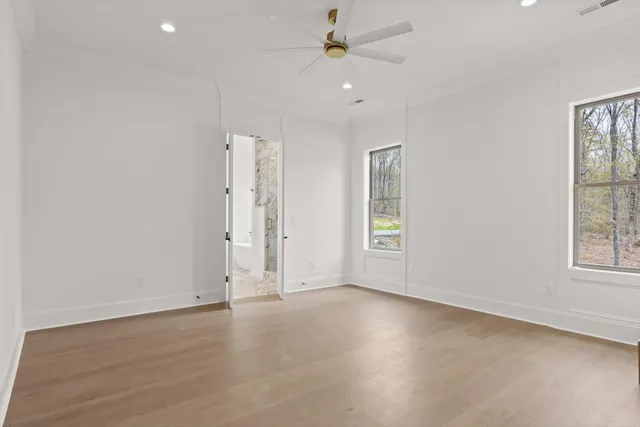 an empty room with windows and ceiling fan