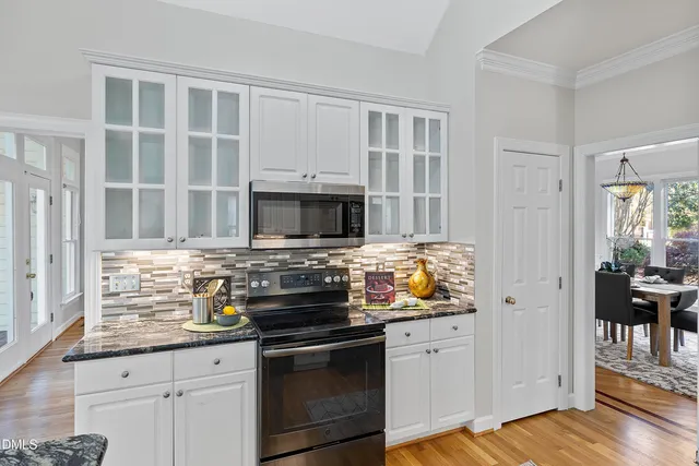a dining room with wooden floor a chandelier a wooden table and chairs