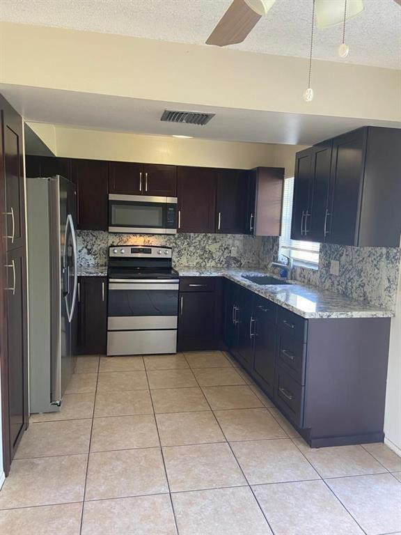 939 Burn Drive Northeast Palm Bay, FL 32905 - Photo 9 of 15 a kitchen with stainless steel appliances granite countertop a refrigerator and a sink