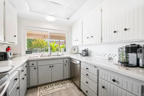 a kitchen with granite countertop a sink white cabinets and window