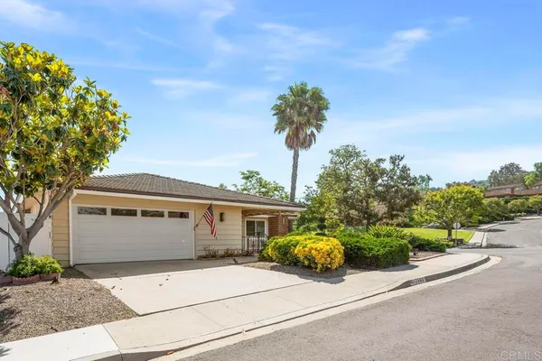 a front view of a house with a garden and a tree