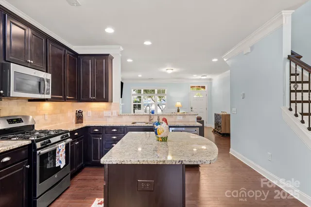 a kitchen with stainless steel appliances granite countertop a sink stove and microwave