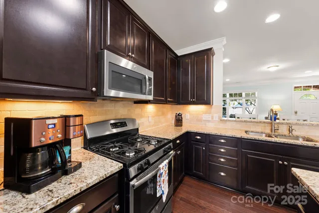 a kitchen with granite countertop a sink a stove and cabinets