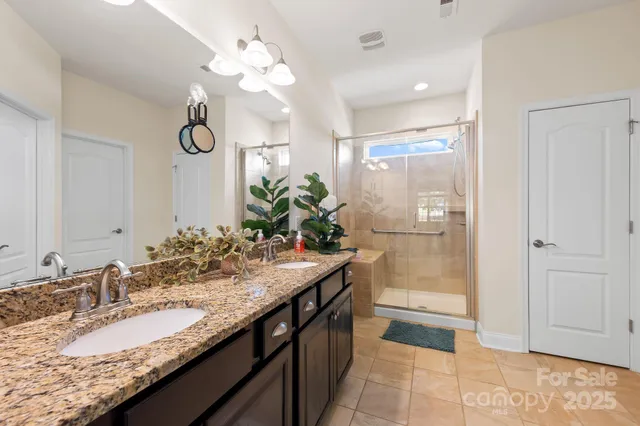 a bathroom with a granite countertop sink a large mirror and a shower