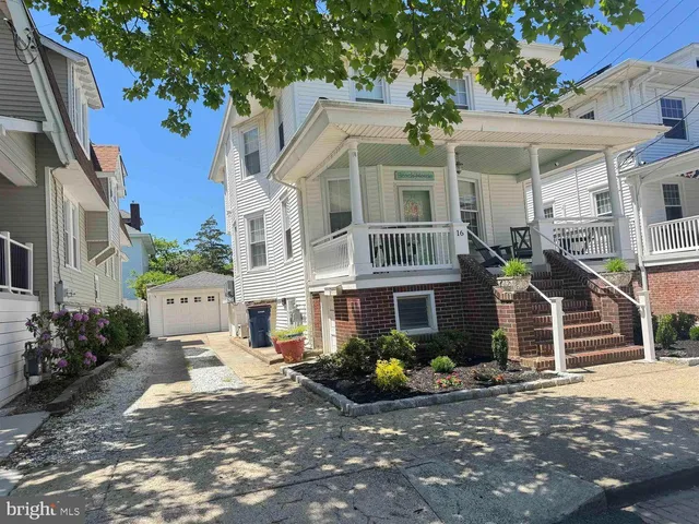 a view of a white house with large windows and a street