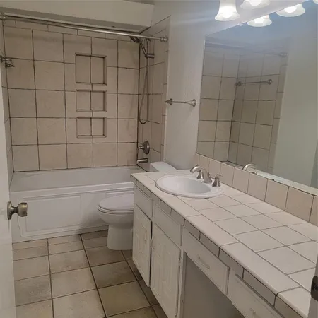 a bathroom with a granite countertop sink a toilet and shower