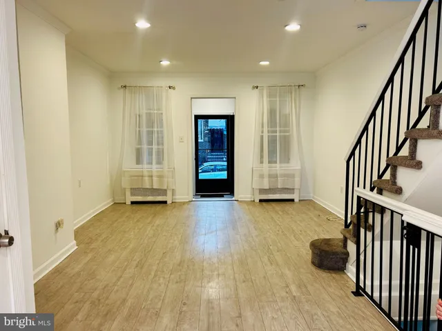 an empty room with wooden floor and stairs