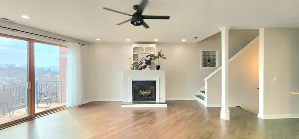 a view of an empty room with wooden floor and windows