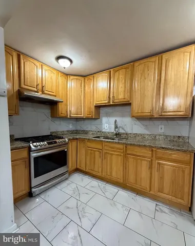 a kitchen with granite countertop a stove sink and cabinets