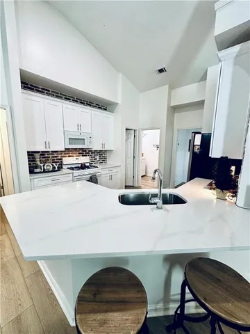a kitchen with stainless steel appliances a white table and chairs in it
