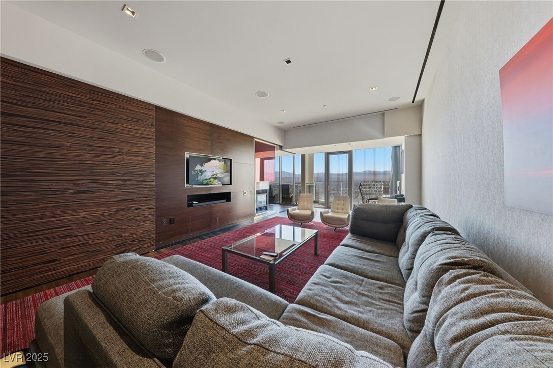 4381 West Flamingo Road, Unit 58301 Las Vegas, NV 89103 - Photo 11 of 32 Living room with wooden walls, a glass covered fireplace, recessed lighting, and wallpapered walls