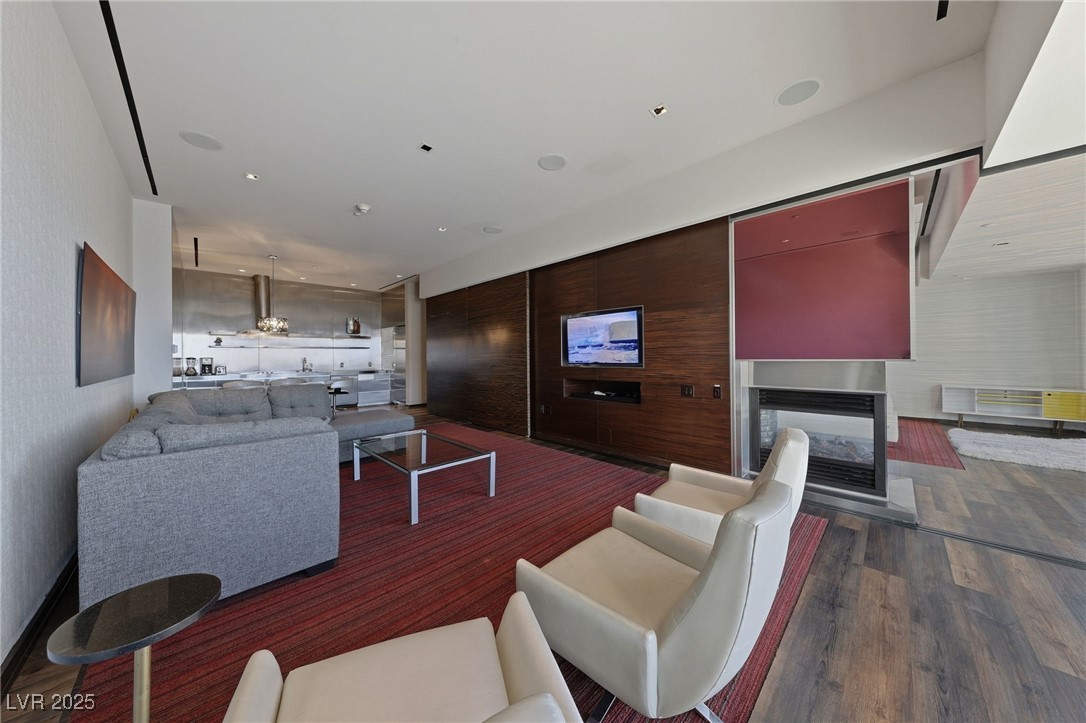 4381 West Flamingo Road, Unit 58301 Las Vegas, NV 89103 - Photo 13 of 32 Living room with a multi sided fireplace, recessed lighting, and dark wood-style flooring