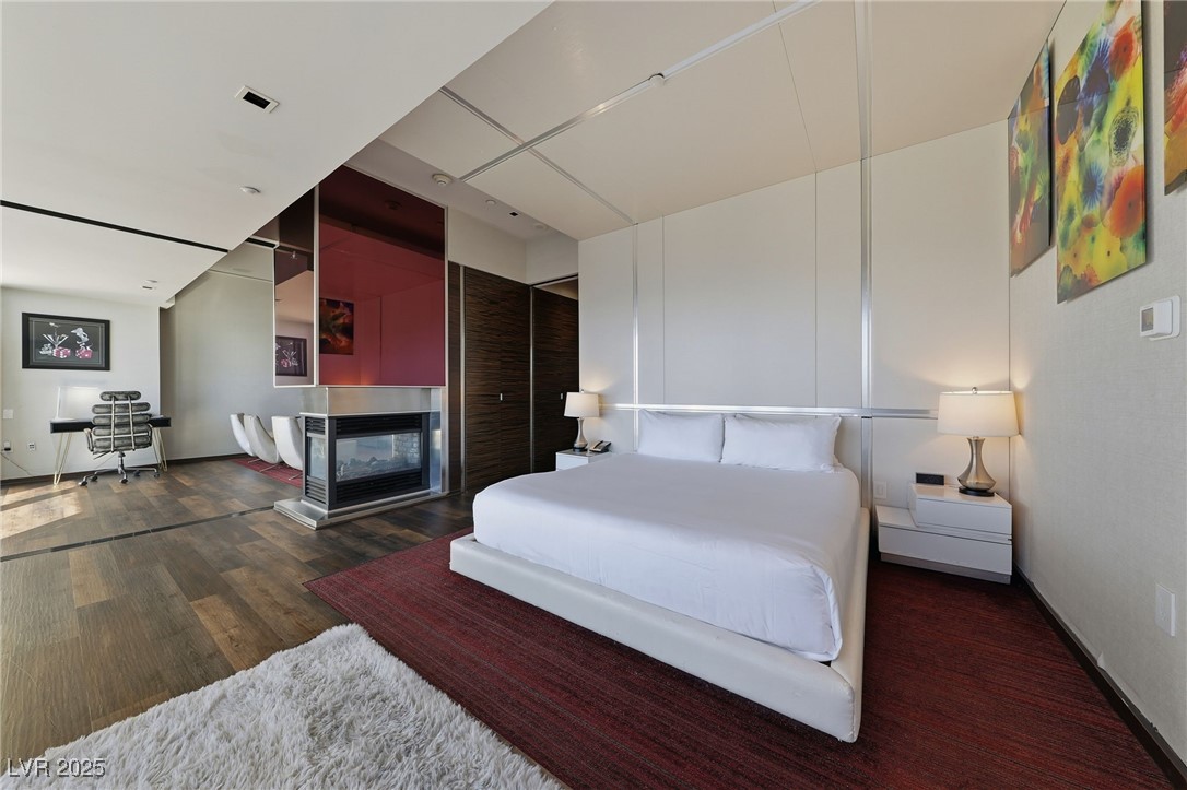 4381 West Flamingo Road, Unit 58301 Las Vegas, NV 89103 - Photo 16 of 32 Bedroom with a multi sided fireplace and dark wood finished floors