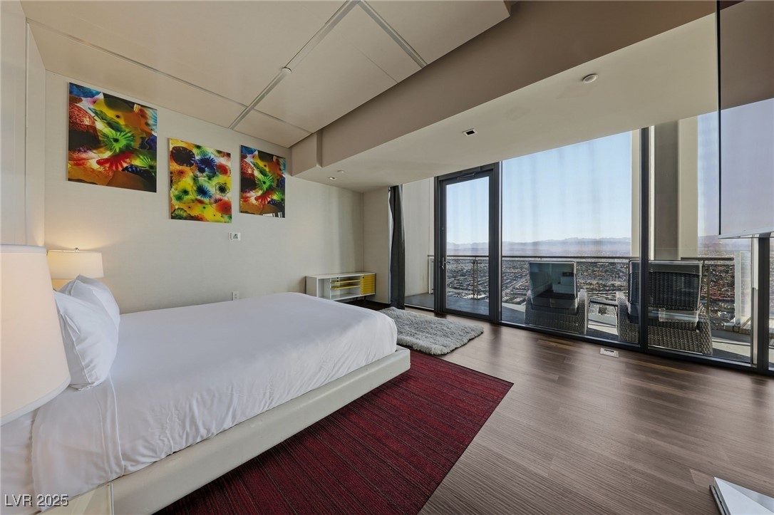 4381 West Flamingo Road, Unit 58301 Las Vegas, NV 89103 - Photo 18 of 32 Bedroom with expansive windows, wood finished floors, and access to exterior