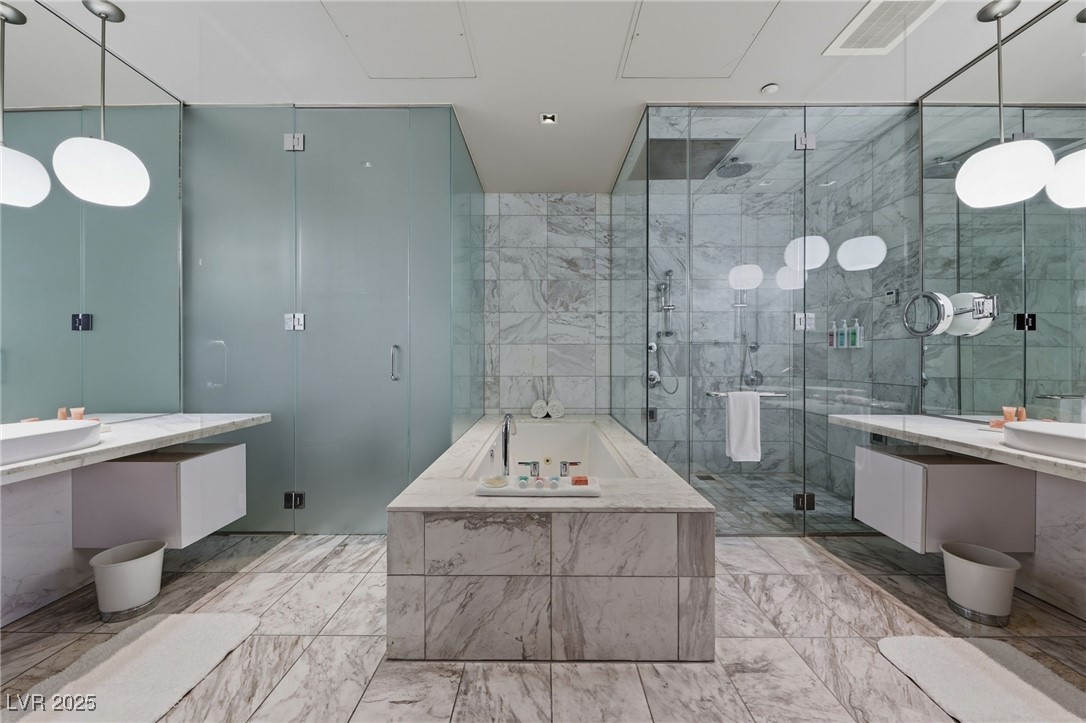 4381 West Flamingo Road, Unit 58301 Las Vegas, NV 89103 - Photo 20 of 32 Full bathroom with a bath, two vanities, tile walls, and a marble finish shower