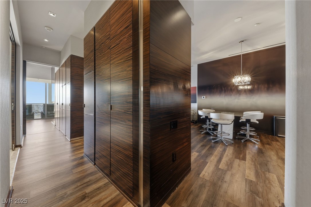 4381 West Flamingo Road, Unit 58301 Las Vegas, NV 89103 - Photo 7 of 32 Corridor with dark wood-style flooring and a chandelier