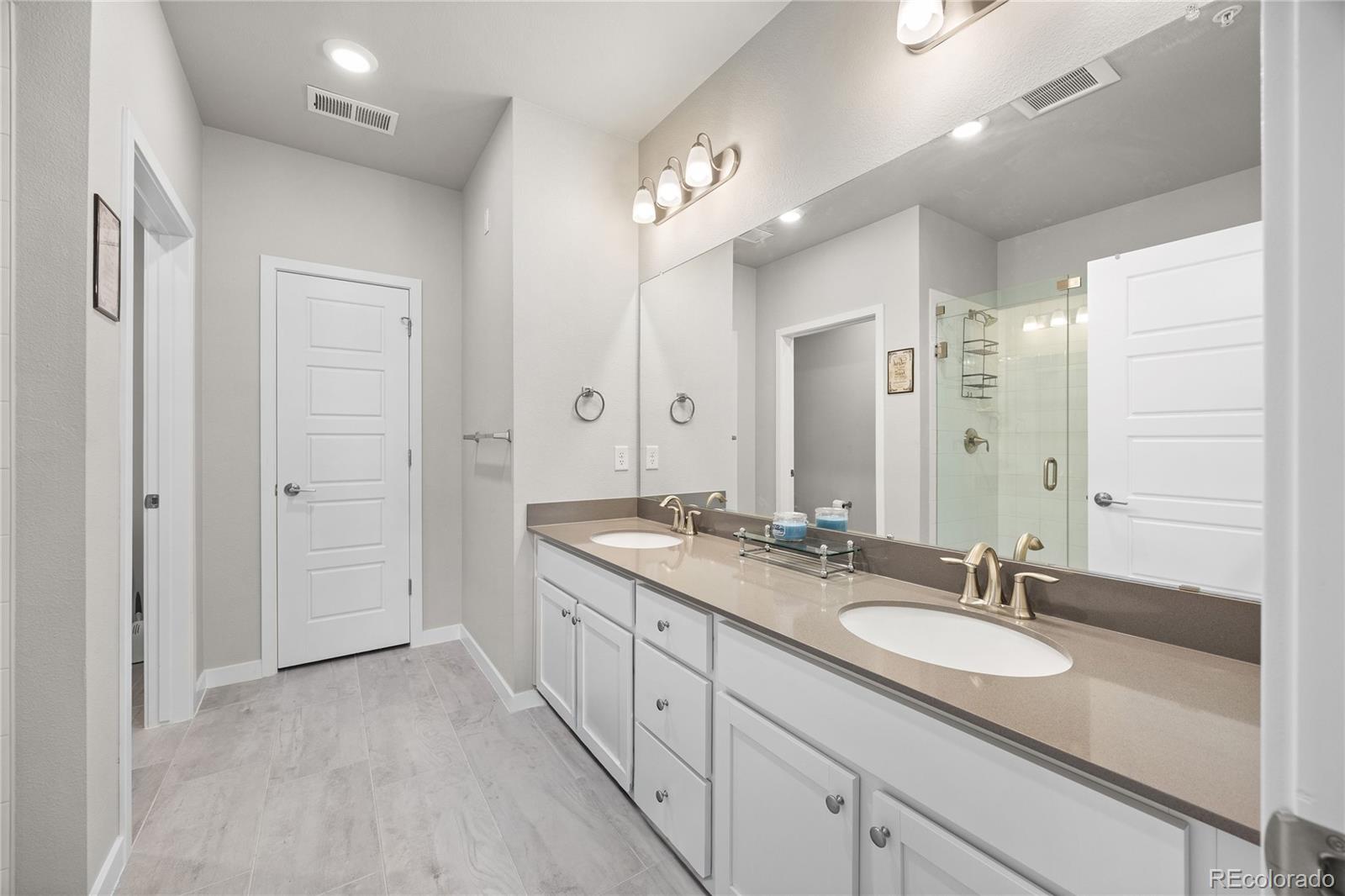 9291 Twenty Mile Road, Unit 303 Parker, CO 80134 - Photo 16 of 28 a spacious bathroom with a granite countertop sink a mirror and a shower