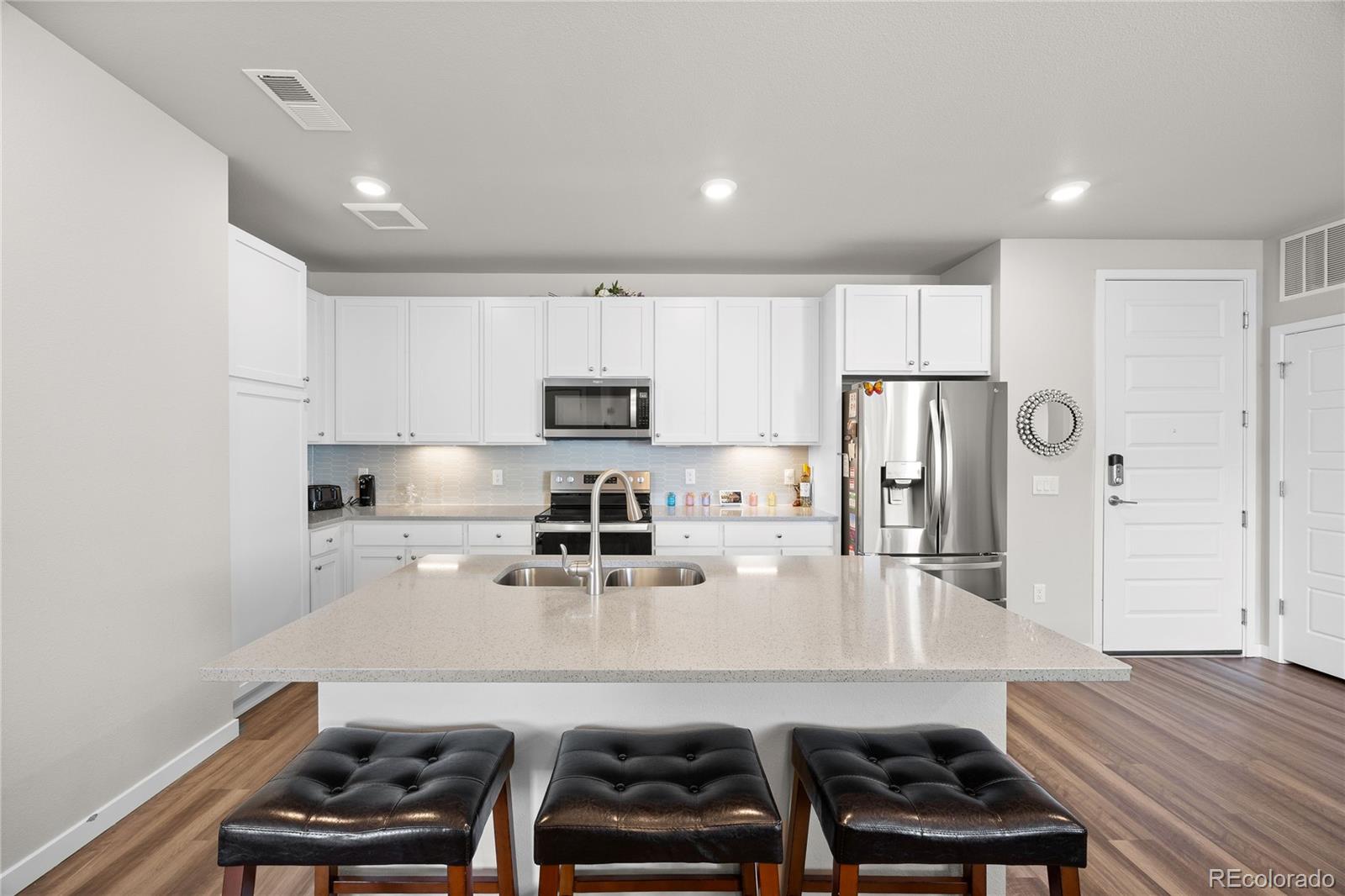 9291 Twenty Mile Road, Unit 303 Parker, CO 80134 - Photo 7 of 28 a kitchen with stainless steel appliances a sink a stove a refrigerator and cabinets