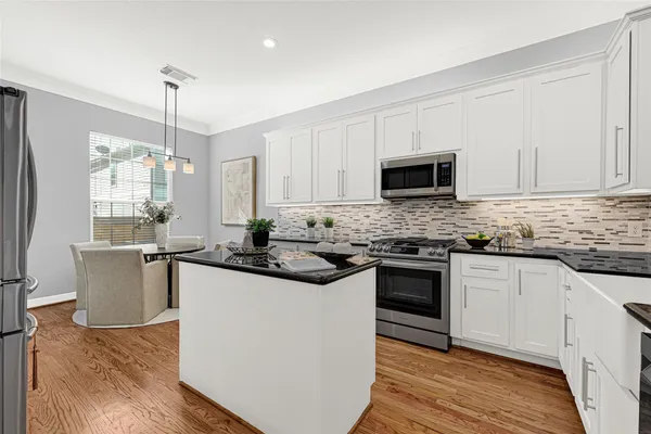 a kitchen with kitchen island granite countertop a sink cabinets and stainless steel appliances