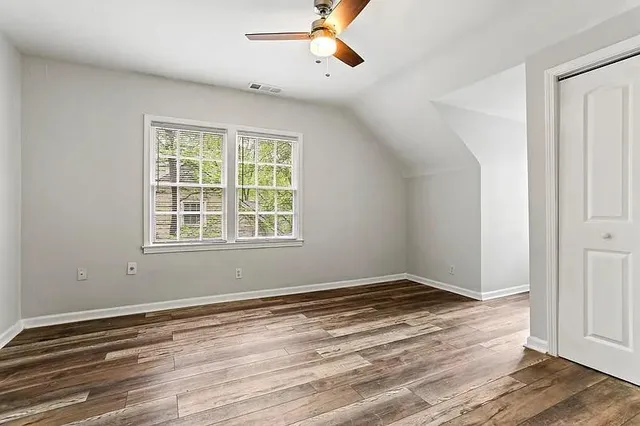 a view of empty room with wooden floor and fan