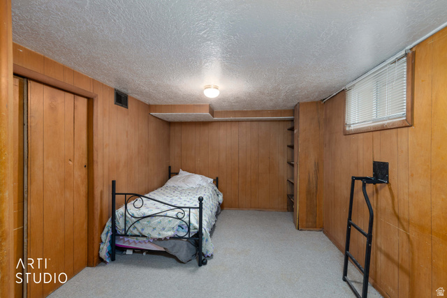875 Patterson Street Ogden, UT 84403 - Photo 22 of 38 Bedroom with a closet, light carpet, wooden walls, and a textured ceiling