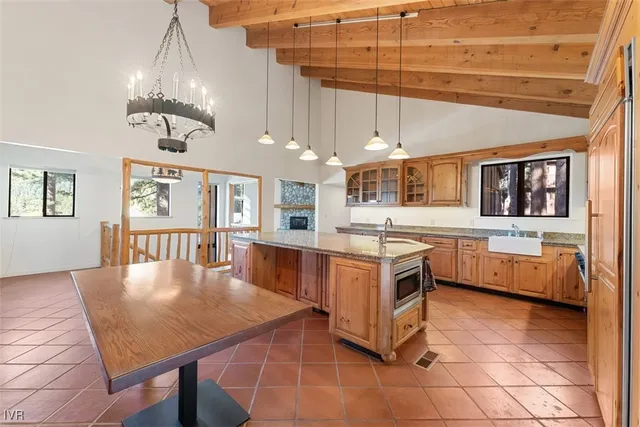 a large kitchen with stainless steel appliances kitchen island granite countertop a table chairs in it and a window