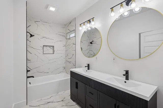 a bathroom with a double vanity sink mirror and bathtub