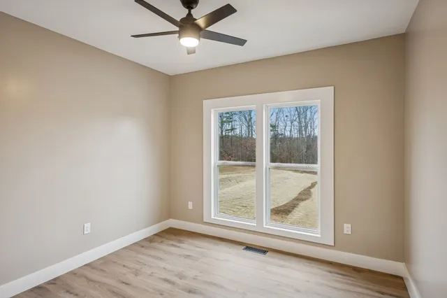 an empty room with wooden floor fan and windows