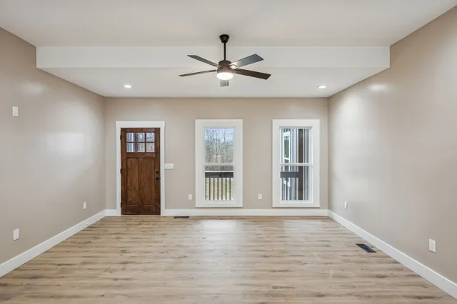 a view of an empty room with window and wooden floor