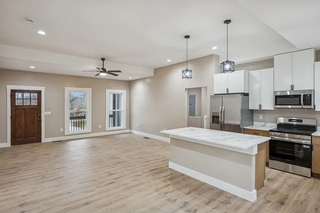 a large kitchen with stainless steel appliances a large counter top a sink cabinets and a wooden floor