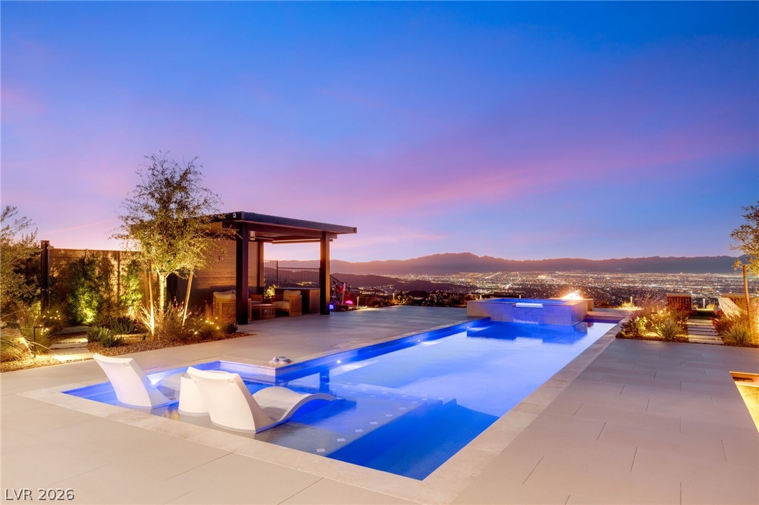 571 Overlook Rim Drive Henderson, NV 89012 - Photo 63 of 85 Pool at dusk featuring a pool with connected hot tub, a mountain view, and a patio