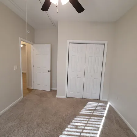 an empty room with closet and a chandelier fan