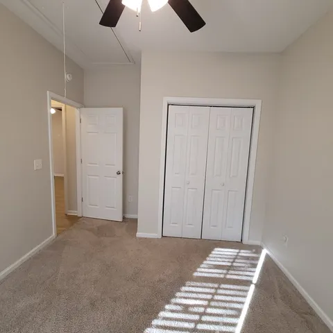 an empty room with closet and a chandelier fan