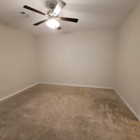 an empty room with a fan & a ceiling fan